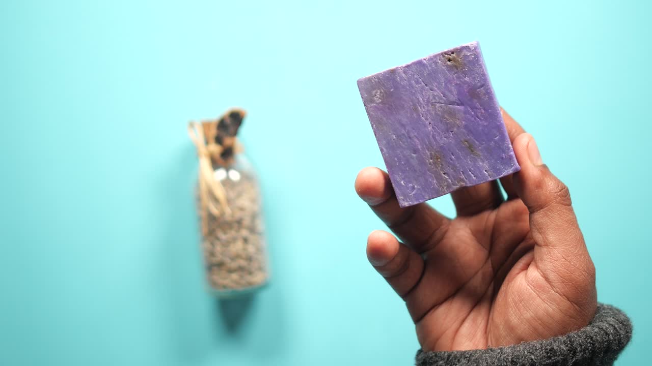 라벤더 비누 한 조각 을 들고 있는 손