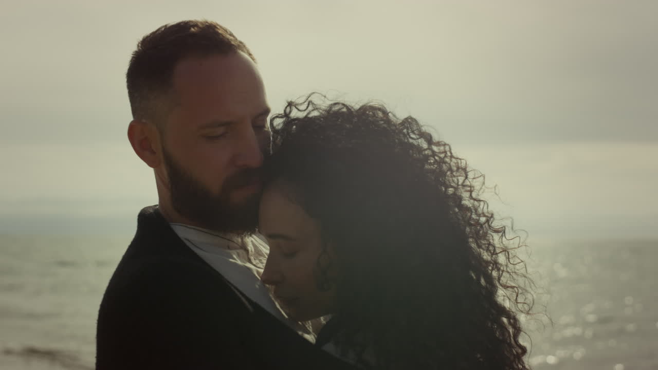 Young people cuddling outdoors. Married couple embracing at sea beach shore.
