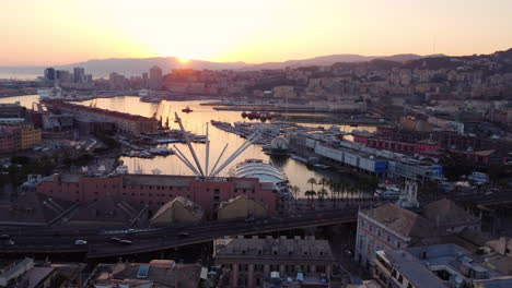 drone flies backward and slightly upward over genoa historic port at sunset, showing traffic, city, and mountains in the background