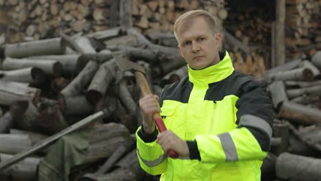 Lumberjack-in-reflective-jacket.-Man-woodcutter-with-small-axe.-Sawn-logs,-firewood-background