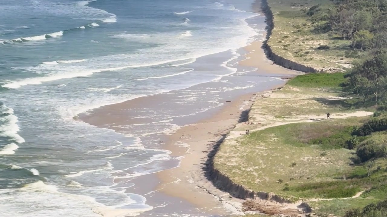 Imagem Aérea de Drone Mostrando Ondas Impactando uma Praia Arenosa e Dunas Costeiras Erodidas