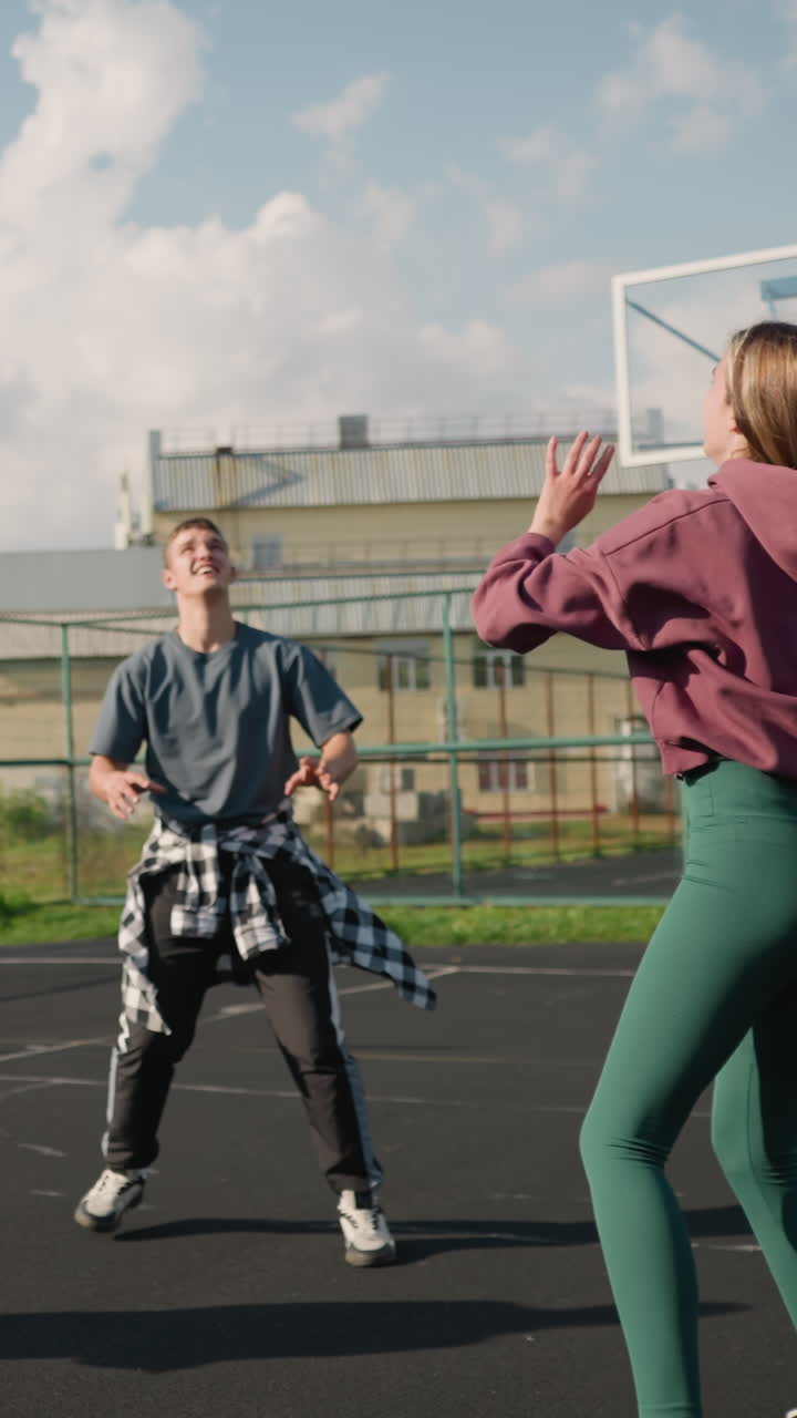 el entrenador conduce una sesión de entrenamiento con tres damas pasando voleibol entre ellas en la cancha al aire libre, demostrando el trabajo en equipo y la práctica con la cancha de baloncesto y el fondo de la construcción