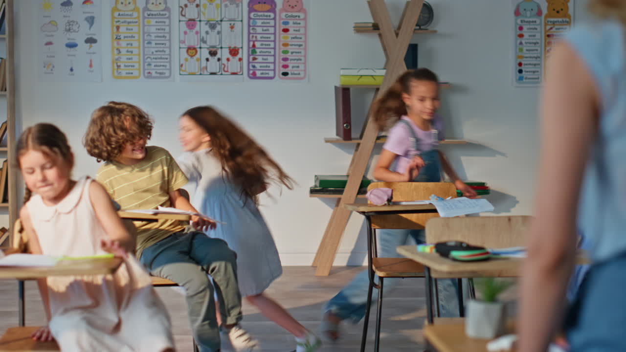 Happy schoolgirls clapping hands inside classroom. Two students playing game