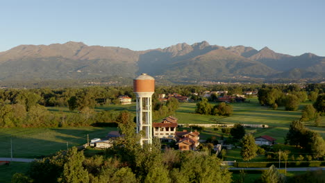 torre de agua de mampostería o piezométrica en la verde campiña de sandigliano con montañas en el fondo biella, piamonte en italia