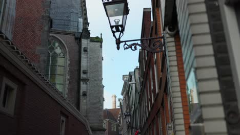 Die-Neigung-Nach-Oben-Zeigt-Eine-Schmale-Gasse-Und-Historische-Backsteingebäude-In-Amsterdam,-Niederlande