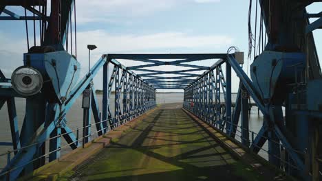 retrocediendo de un puente oxidado y bajo una grúa abandonada en el muelle abandonado en los muelles de fleetwood, lancashire, reino unido