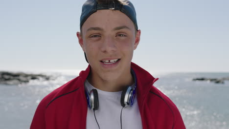 cool trendy teenager portrait of boy smiling happy on sunny beach looking at camera wearing hat enjoying summer