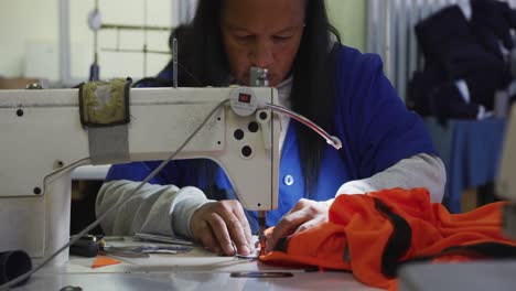 mixed race woman using sewing machine in factory