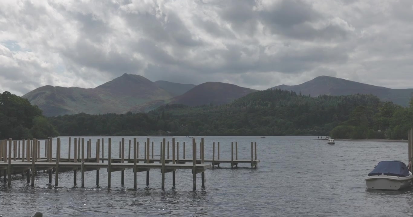 Perbukitan dramatis yang menghadap ke dermaga kayu di Danau Windermere di Lake District