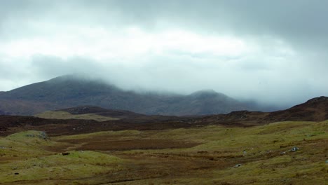 Static-shot-of-a-misty-mountain-range-behind-a-peatland-moor-covered-in-heather