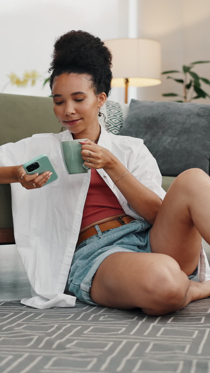 Giovane donna che si rilassa a casa, beve caffè e usa lo smartphone