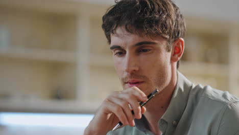 portrait attractive serious man sitting kitchen. pensive freelancer working home