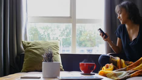 Vista-Frontal-De-Una-Joven-Asiática-Usando-Teléfono-Móvil-En-Casa-4k