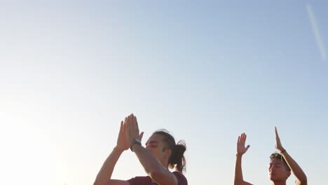 happy diverse gay male couple doing yoga and meditating at promenade by the sea, slow motion