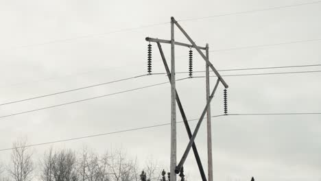 Langsame-Nahaufnahme,-Bewölkter-Himmel,-Schwenk,-Schuss,-Großes-Hölzernes-Stromnetz,-Telefonübertragungsturm,-Elektrischer-Mast,-Der-Hochspannungsstrom-über-Weite-Strecken-Im-Freien-Transportiert,-Energieinfrastruktur