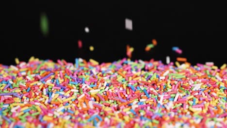 rainbow sprinkles cascade against a black background