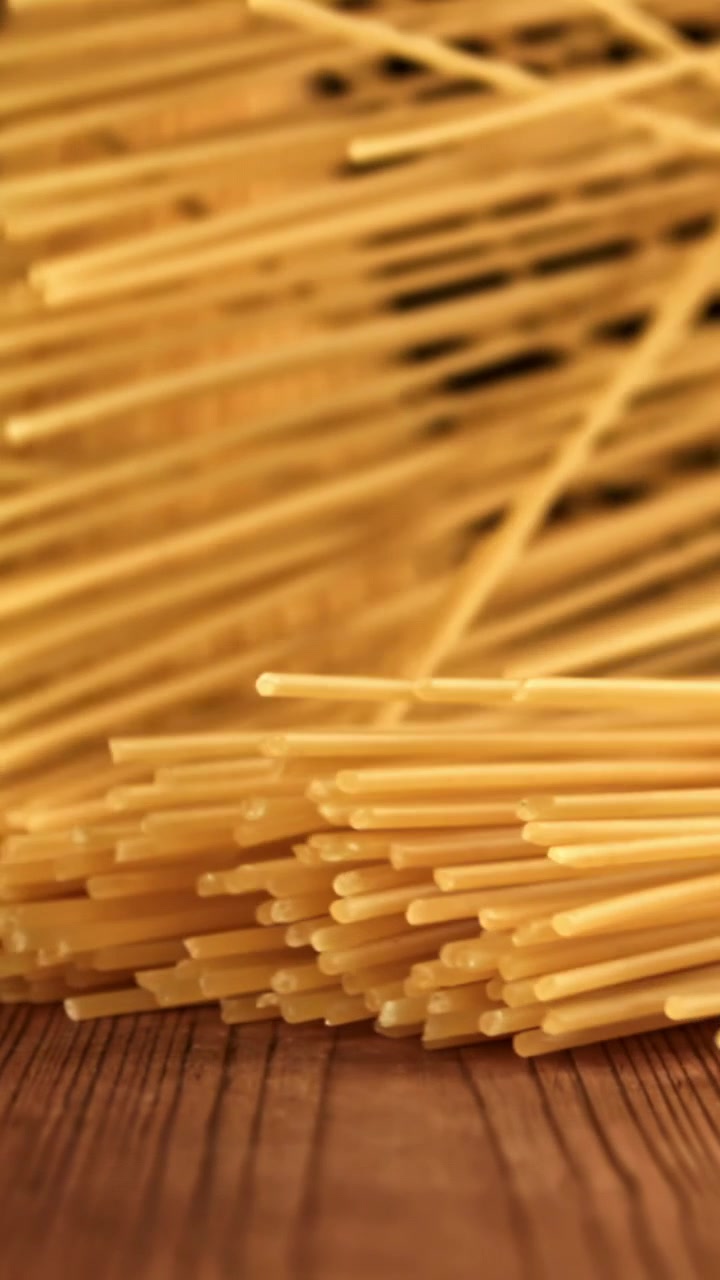 Spaghetti crudi che cadono su un tavolo di legno