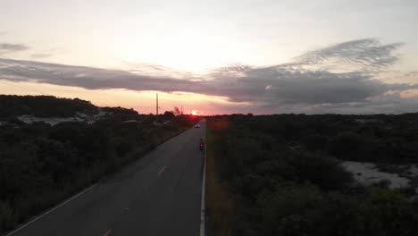 aerial shot along the road: driving a motocycle and sunset