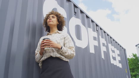 retrato de la propietaria de una cafetería o negocio de distribución de pie junto al contenedor de envío