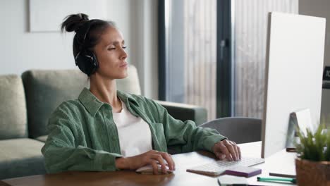 Focus-young-caucasian-woman-wearing-headphones-and-working-on-computer