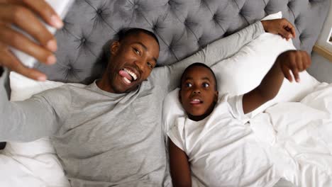 father and son taking selfie with mobile phone in bedroom 4k