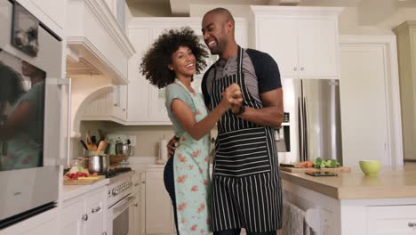 Glückliches-Gemischtrassiges-Paar,-Das-In-Seiner-Küche-Kocht-Und-Tanzt