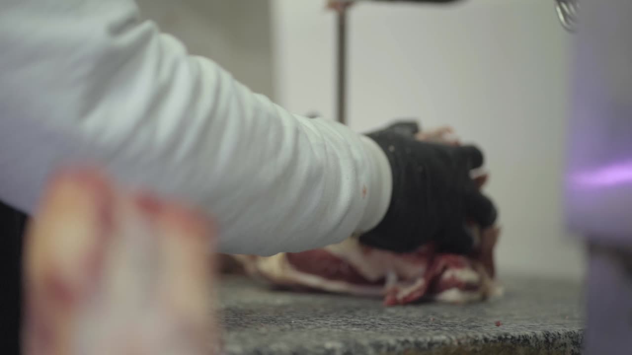Close-up of Hispanic man working in butcher shop with meat saw. Economic growth. Argentina.