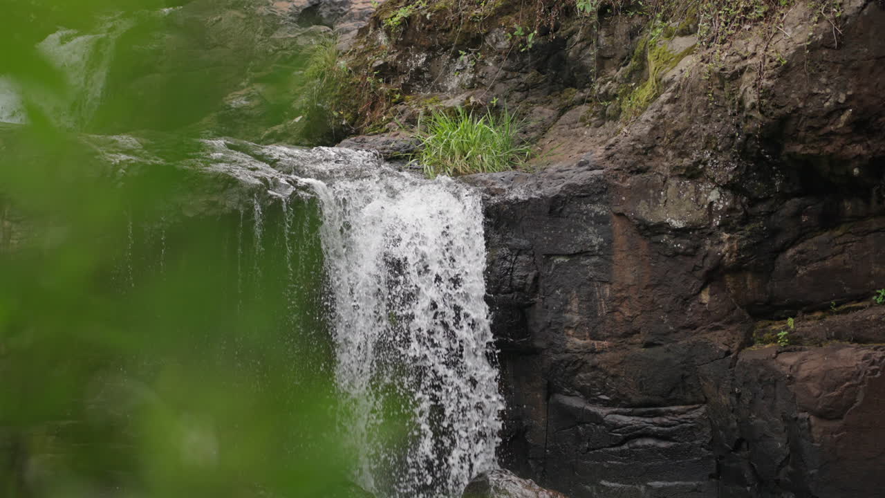Water cascades over rocky cliffs at Salto El Yerba in Misiones, Argentina. Lush greenery surrounds the waterfall, creating a serene and natural landscape, revealing shot, slow motion