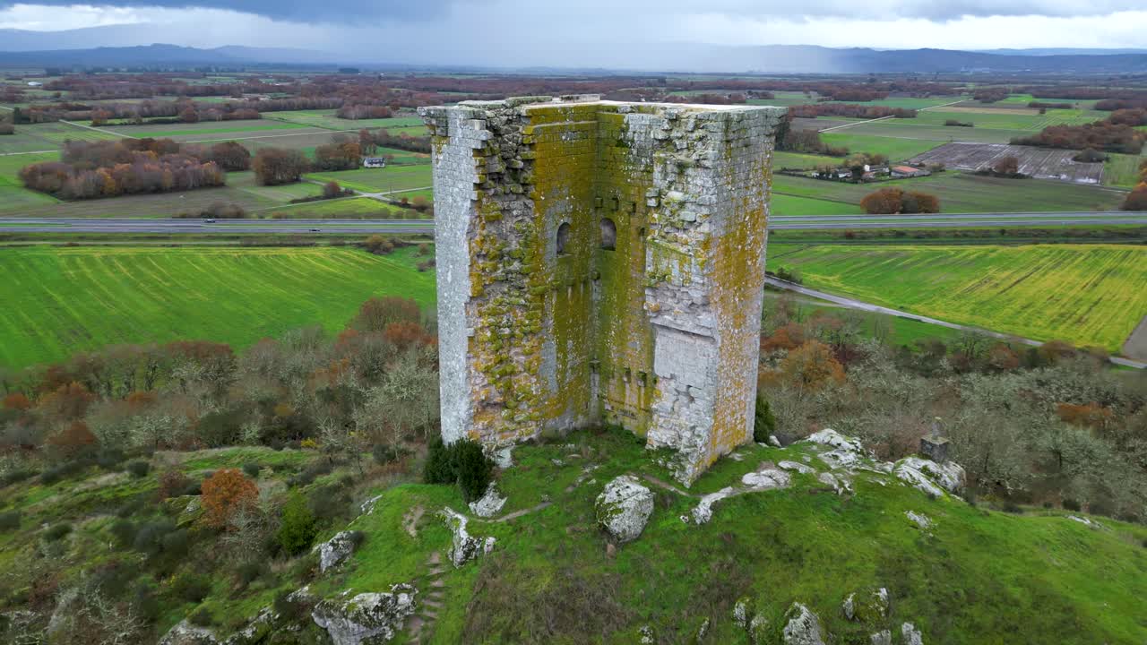 Aerial pullback reveal Sandi&aacute;s tower, ourense, spain, near highway, mossy