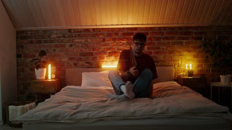 young man relaxing in bedroom with tablet