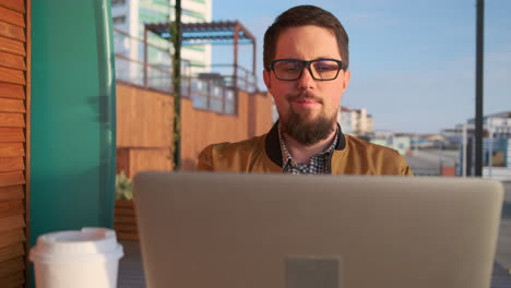 hombre trabajando en una computadora portátil en un café al aire libre