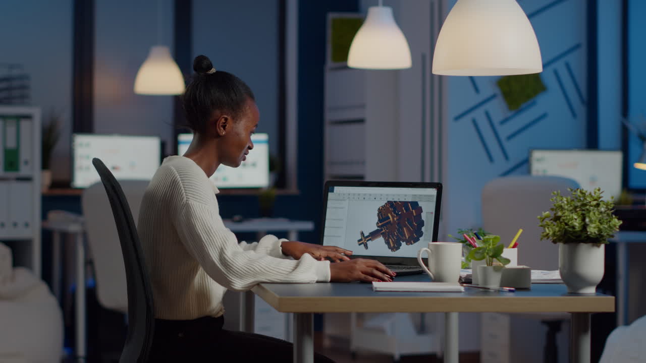 ingeniero africano trabajando tarde en la noche en un modelo 3d de engranajes industriales