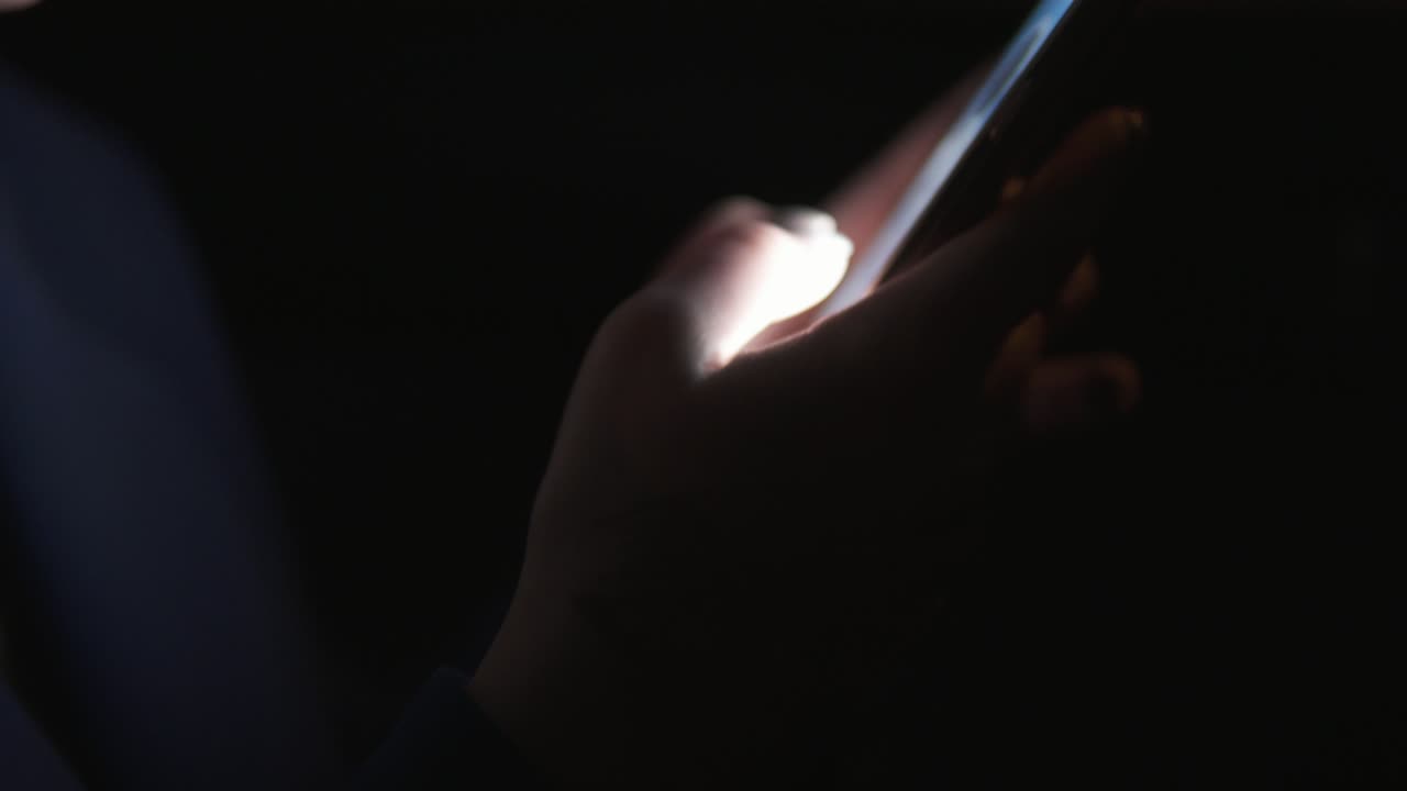 Close Up view of woman's hands texting using her smartphone. Woman riding in taxi late at night. Night live. Slow Motion shot