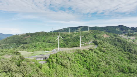 majestic aerial footage of elongated wind turbines atop rolling hills