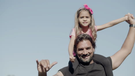 pensive little girl sitting on fathers neck and holding hands