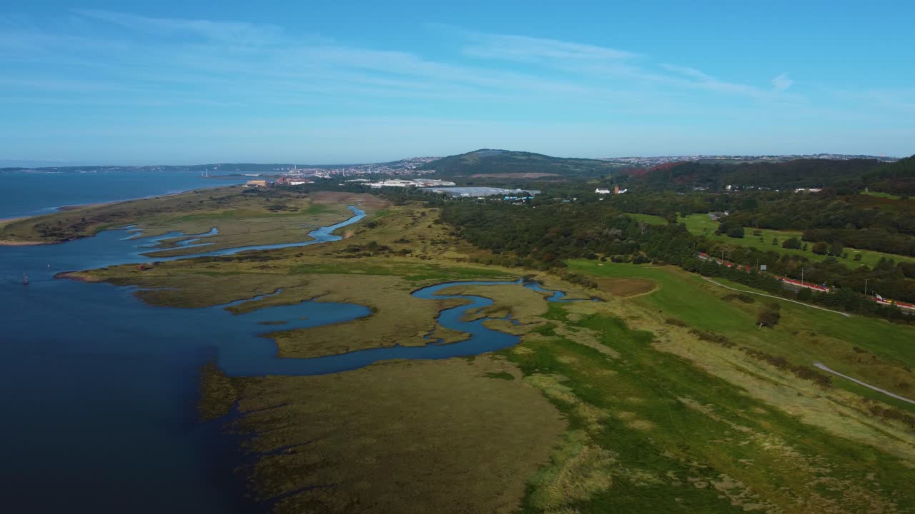 Drone View of Natural Wetlands Landscape at High Tide with Swansea Bay in Background with Warehouse and Winding Rivers