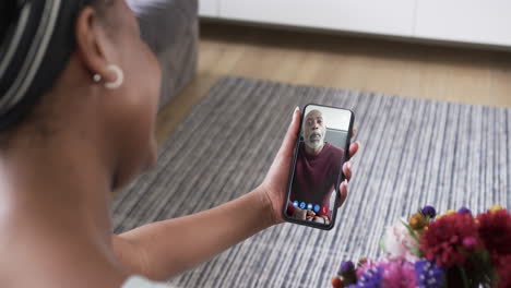 mujer afroamericana sosteniendo un teléfono inteligente con un hombre afroamericano en la pantalla