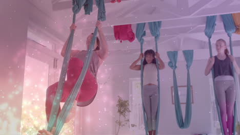 animación de partículas brillantes sobre diversas instructoras y adolescentes practicando yoga aéreo