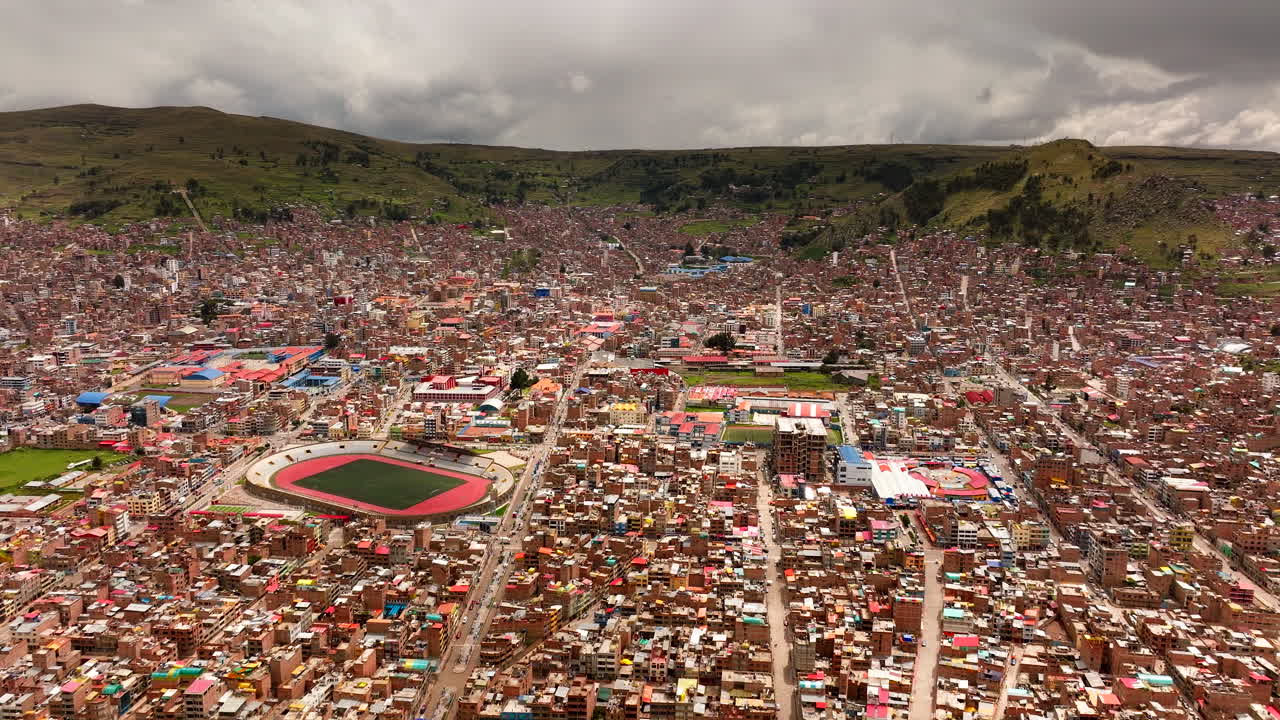 Widok z drona na gęsto zaludnioną miejską panoramę i stadion piłkarski na brzegach jeziora Titicaca w Puno, Peru. Lot do przodu
