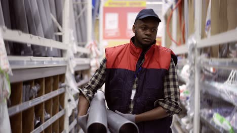 workman walks with water pipes in plumbing or hardware store