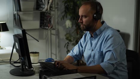 oficina masculina trabajando, trabajando hasta tarde mientras escucha música con auriculares