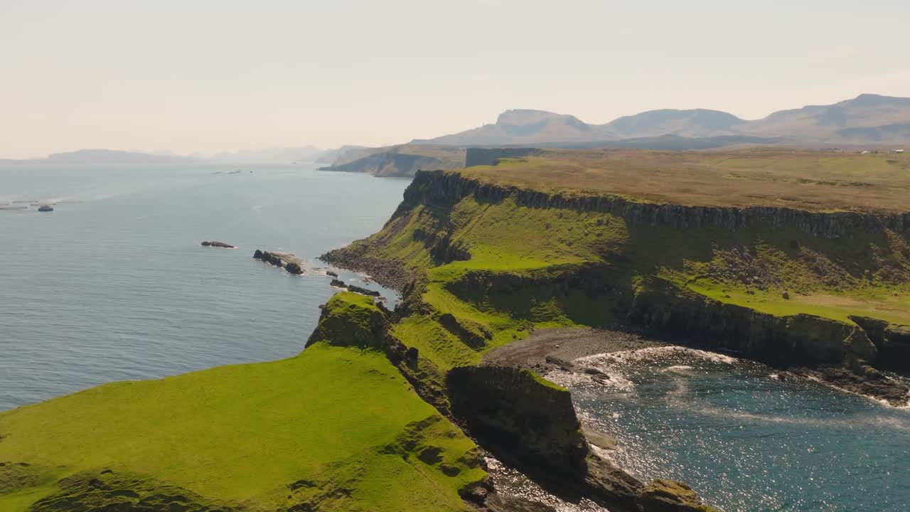 Aerial drone footage of dramatic sea cliffs along the rugged Scottish coastline on the Isle of Skye. Towering rock formations, crashing waves, and breathtaking views