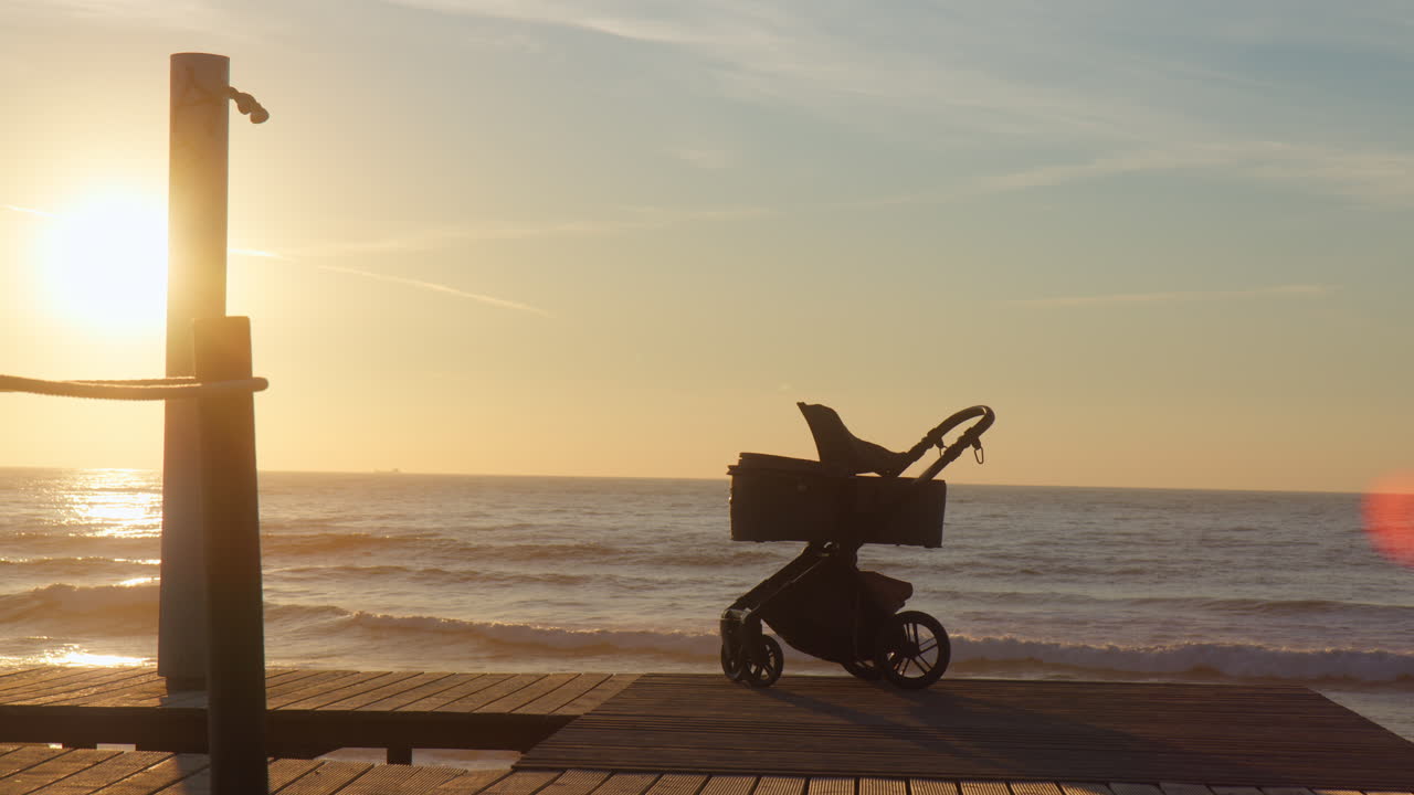 Baby pram on a beach promenade at sunset. Happy childhood