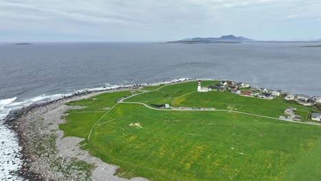 alnes lighthouse at peninsula outside alesund norway - aerial showing red and white lighthouse surrounded by green grass with north sea in background