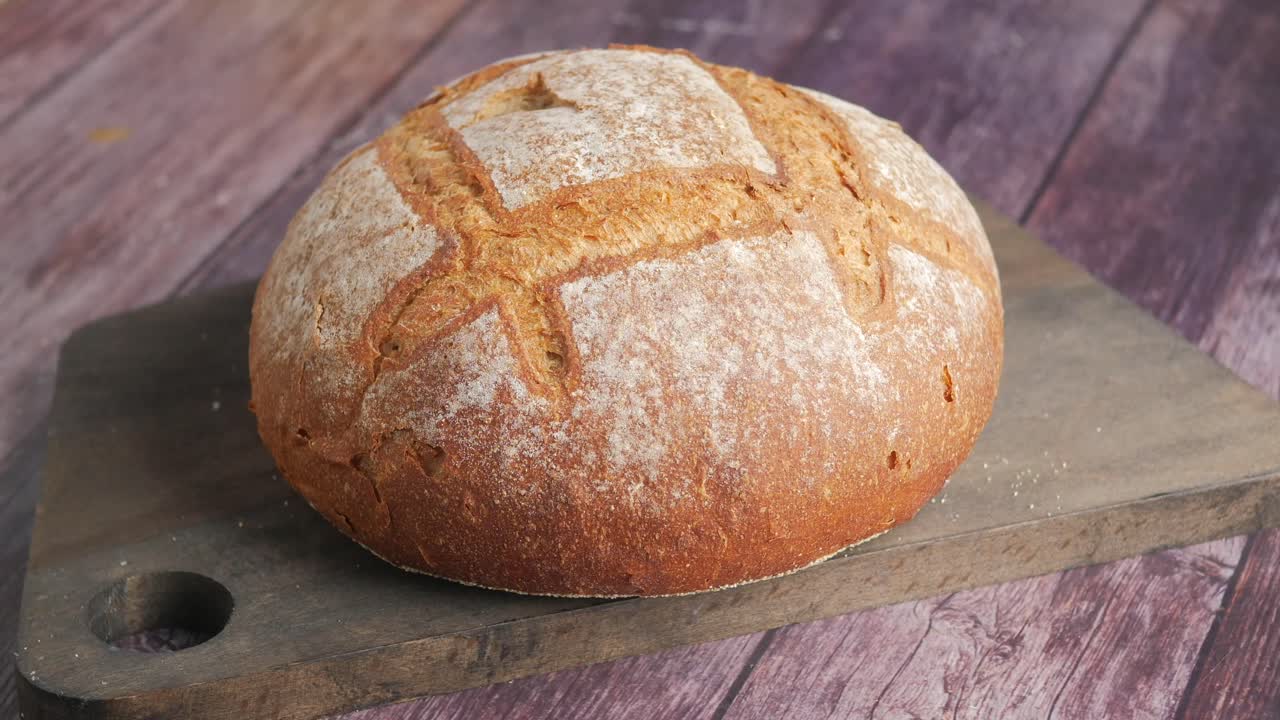 Freshly Baked Round Loaf of Rustic Bread on a Wooden Board