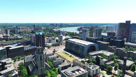 Die-Drohne-Fliegt-über-Das-Stadtzentrum-Von-Rotterdam-Mit-Dem-Markthal-In-Der-Mitte-Und-Dem-Fluss-Im-Hintergrund-In-Rotterdam,-Niederlande,-Luftaufnahmen-4K