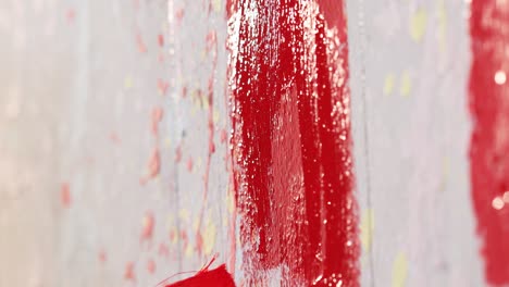 a man is painting a wall in red color with brush,close up shot,insert shot