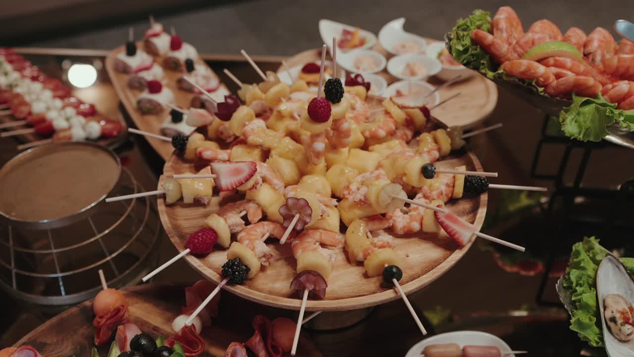 shrimp and fruit skewers with berries pineapple and grapes served on wooden platter at buffet