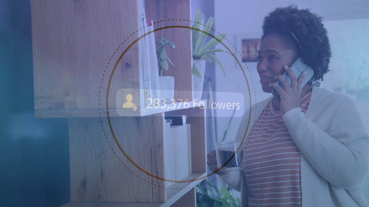 Woman by shelf, on phone holding mug watching follower overlay appearing and tracking social growth