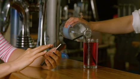 mujer siendo servida una bebida en el bar